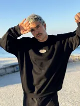 Buzo negro oversize con cuello redondo y logo ovalado bordado en el pecho.