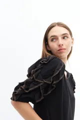 Remera color beige con mangas cortas y volados con borde naranja.