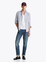 Camisa de mangas largas a rayas verticales azules y blancas, confeccionada en popelín de puro algodón con tecnología Flex que le confiere elasticidad. Tiene cuello abotonado, puños redondeados con botón y logo de Tommy Hilfiger bordado en el pecho.