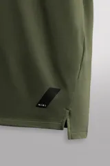Camiseta deportiva verde militar confeccionada en tejido estructurado, ligero y elástico. Tiene cuello redondo, manga corta y bajo con aberturas laterales. Incluye logo estampado en el bajo.