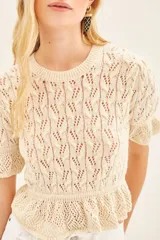 Sweater color crema tejido con punto desagujado en hilado de algodón y poliéster. Tiene ajustes en mangas y cintura, y pequeños volados en las terminaciones.