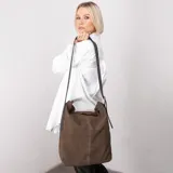 Cartera tipo bucket de cuero graneado color marrón, con correa de cuero engrasado regulable y hebilla metálica con forma de estribo. Interior 100% algodón.