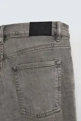 Pantalón de jean negro, corte slim fit, con tiro medio, cinco bolsillos, efecto lavado y cierre frontal con cremallera y botón.