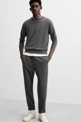 Pantalón negro de corte cropped, con cintura elástica ajustable con cordón, bolsillos laterales y traseros de vivo. El bajo tiene terminación con vuelta.