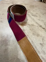 Cinturón de cuero marrón con apliques de tela aguayo con motivos geométricos multicolores.