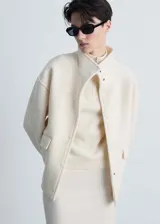 Chaqueta color crema de mezcla de lana con cuello alto y cierre de botones oculto.