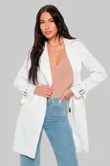 Trench largo color blanco de cuero vegano, con cuello solapa, cierre cruzado con lazo y bolsillos laterales.