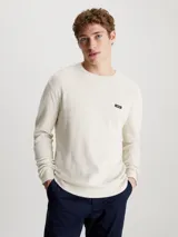 Sweater de punto color crema, de corte recto, con cuello redondo y logo de Calvin Klein en el pecho.