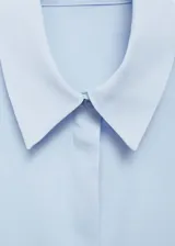 Camisa negra de tejido fluido, corte recto, cuello camisero, manga larga con puños abotonados y cierre frontal con botones.