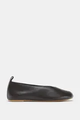 Zapato tipo bailarina de piel color negro, con abertura en la parte delantera y detalle de tira trasera. Suela plana de 1 cm de altura.