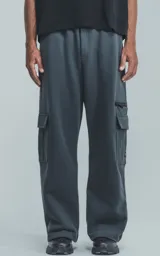 Pantalón de jogging gris oscuro, de corte amplio, con cintura y puños elásticos, bolsillos laterales y trasero, y bolsillo lateral adicional con cierre.
