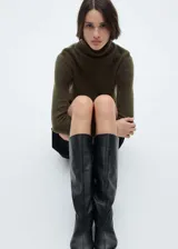 Sweater color beige de tejido de punto con cuello alto y mangas largas.