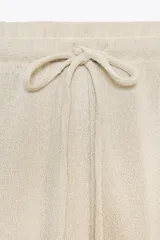 Pantalón de punto color beige, de tiro alto con cintura elástica ajustable con cordones y corte ancho.