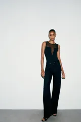 Body negro de cuello redondo y sin mangas, con parte superior de tul transparente y cierre inferior con broches a presión.
