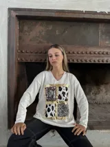 Remera blanca de manga larga con cuello en V y estampado con recuadros de animal print en el frente.
