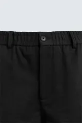 Pantalón de vestir color blanco hueso, de corte recto y tiro medio, con cintura elástica y cierre frontal de botón y cremallera. Presenta bolsillos frontales y bolsillos traseros de vivo.