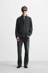 Camisa negra relaxed fit confeccionada en tejido fluido con mezcla de viscosa. Tiene cuello solapa, manga larga con puño abotonado y cierre frontal con botones.