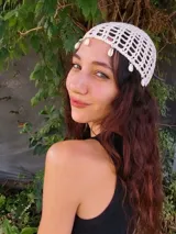 Gorro de crochet negro con diseño calado y apliques de caracoles blancos.