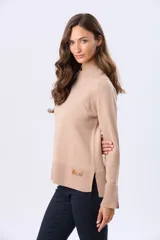 Buzo tejido de lana color beige con cuello alto, calce cómodo y diseño minimalista. Presenta puños y ruedo acanalados, con una pequeña etiqueta de marca aplicada en el lateral.