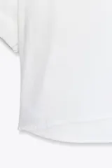Camisa azul de cuello solapa y manga corta con dobladillo. Tiene dos bolsillos de parche en el pecho, bajo asimétrico con aberturas laterales y cierre frontal con botones ocultos.