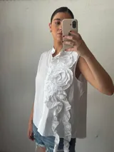 Camisa blanca sin mangas con cuello mao y volados en el frente.