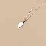Conjunto de dos dijes de corazón en plata 925, cada uno representando una mitad, con cadena veneciana de 45 cm y cadena forcé de 50 cm.