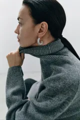 Sweater gris de lana con cuello alto, corte oversize y mangas largas acampanadas.