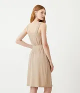 Vestido midi color beige con breteles anchos, escote cuadrado, botones frontales, bolsillos laterales y cinturón de tela con hebilla.