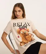 Remera de algodón color crema con estampa de oso de peluche con anteojos y pañuelo rojo en la cabeza.