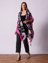 Kimono tejido con estampado floral multicolor, terminación de ruedo con borlas y mangas cortas con borde celeste.