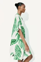 Vestido túnica corto de viscosa con estampado de hojas verdes, cuello mao con abertura en V, mangas cortas, corte holgado y tajos laterales.