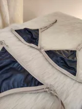 Conjunto de bikini negro con elástico tostado. El corpiño es de corte triangular con breteles regulables y aro metálico en el centro. La bombacha es tipo colaless con tiras laterales regulables.