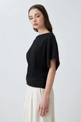 Blusa negra con textura amasada, de mangas cortas y corte holgado.