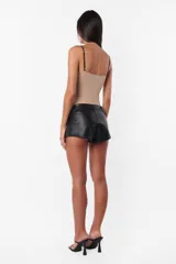 Short negro de cuerina con cierre diagonal desmontable, tiro medio y broches snap en el delantero.