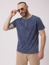 Remera azul con cuello redondo y tapeta con botones. Tiene un acabado desgastado.