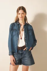 Camisa de manga larga confeccionada en tencel, color azul denim, de corte clásico, con cuello camisero, bolsillos en el frente y botones metálicos.