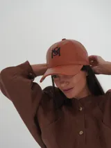 Gorra color ladrillo con logo bordado en verde.