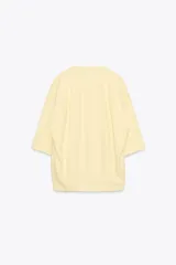 Camiseta color amarillo pastel de corte amplio, cuello redondo y mangas cortas.