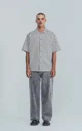 Camisa de manga corta con cuello abierto y corte oversize, a rayas verticales blancas y negras.