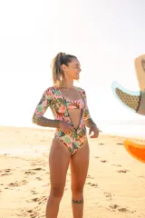 Enterito de surf de lycra Ecocean reciclada con protección SPF 50, estampado con motivos de hojas y cactus en tonos rosa, verde y marrón. Tiene mangas largas con estampado geométrico en los antebrazos, escote en V y cierre frontal con cremallera.
