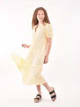 Vestido midi amarillo pastel con bordado calado, cuello mao, mangas cortas abullonadas y falda escalonada.