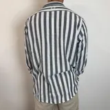 Camisa de lino a rayas verticales color beige y blanco, de corte holgado y manga larga con puños abotonados.