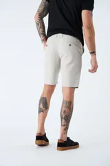 Bermuda color beige de corte chino, con bolsillos laterales, cierre con cremallera y botón, presillas para cinturón y logo bordado. Confeccionada en lino y algodón.