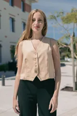 Chaleco corto color beige con escote en V y cierre frontal con botones.