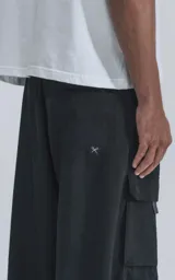 Pantalón técnico negro de silueta oversize, con cintura elástica, bolsillos cargo laterales y un cinturón de cinta con hebilla de plástico.