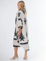 Vestido midi oversized con estampado en fondo negro, cuello tipo camisa, escote en V y tajos laterales.