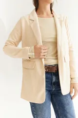 Blazer beige de tela agamuzada, corte recto y solapas clásicas.