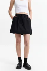 Minifalda negra de algodón con cintura elastizada con lazo regulable y bolsillos laterales.