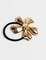 Gomita de pelo elástica negra con aplique de flor dorada de metal.