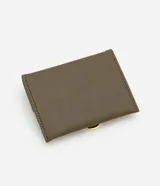 Billetera pequeña color verde oliva, confeccionada en cuero sintético, con cierre de solapa con broche metálico dorado en forma de "D".